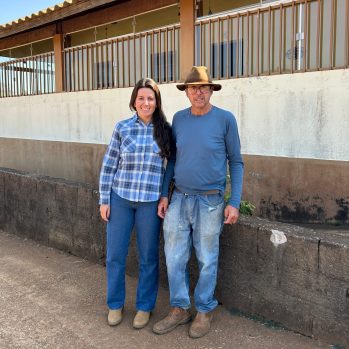 A man and a woman standing next to each other in front of a rustic building
