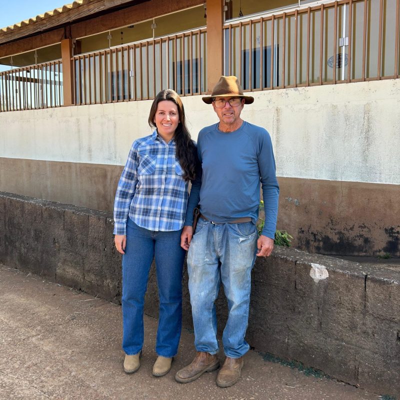 A man and a woman standing next to each other in front of a rustic building