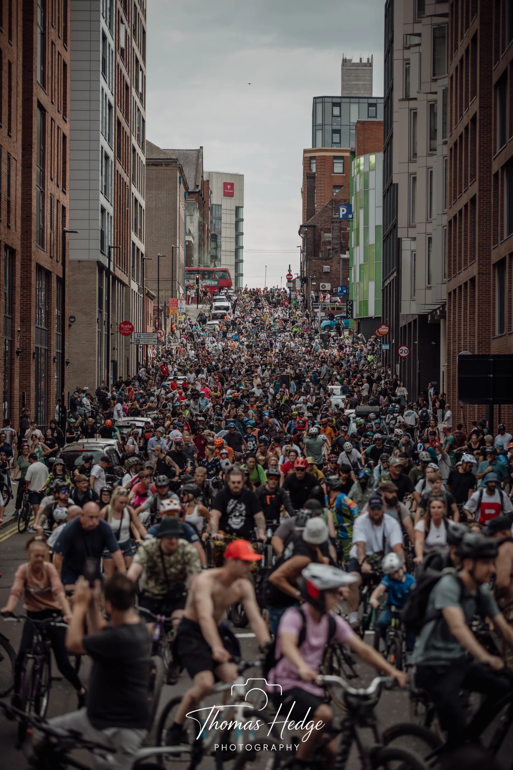 Hundreds, possibly thousands of people on bikes on Rockingham Street, Sheffield during Drum & Bass on the Bike. Taken 16th August 2026 A red circle has been put around Adam's (of Roasting House) face.