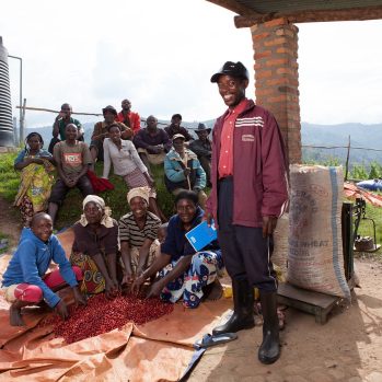 Members of the Rwanda Trading Company stand and sit in front of some red coffee cherries