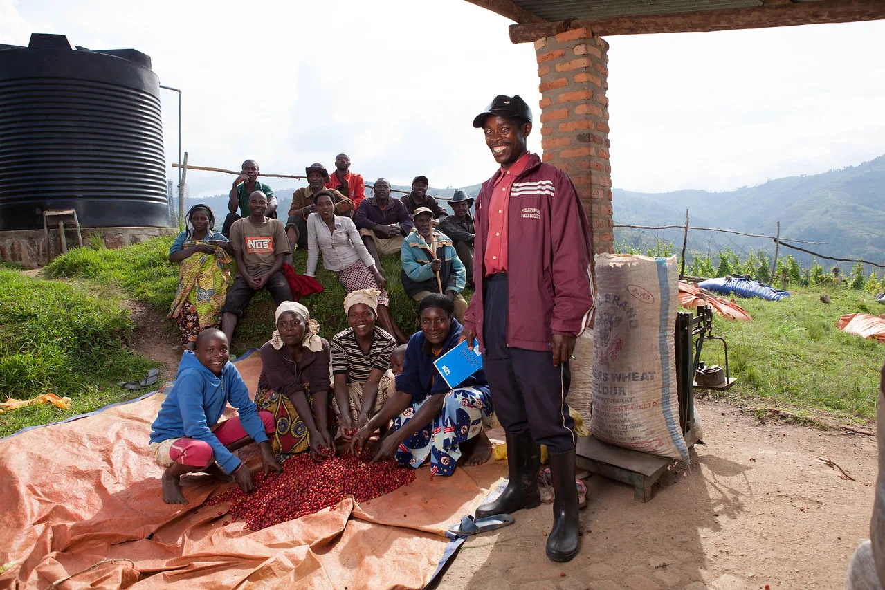 Members of the Rwanda Trading Company stand and sit in front of some red coffee cherries